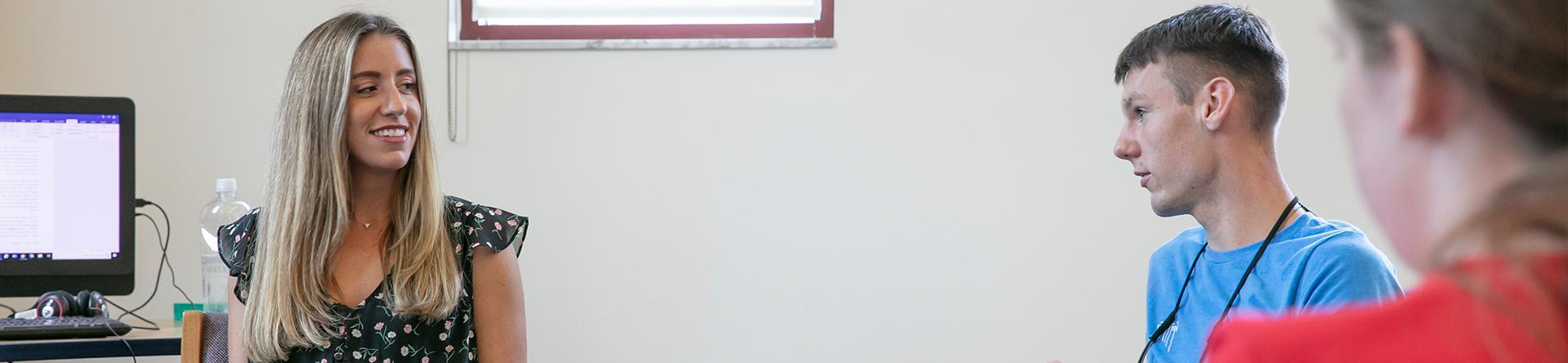 Female teacher smiling in classroom with students who are paying attention